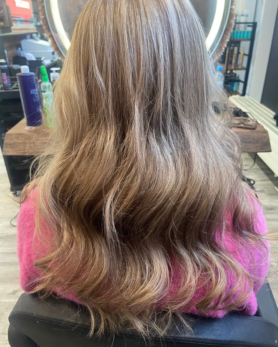 Balayage von Dunkelblond nach Hell, in weichen Wellen gef&ouml;hnt.