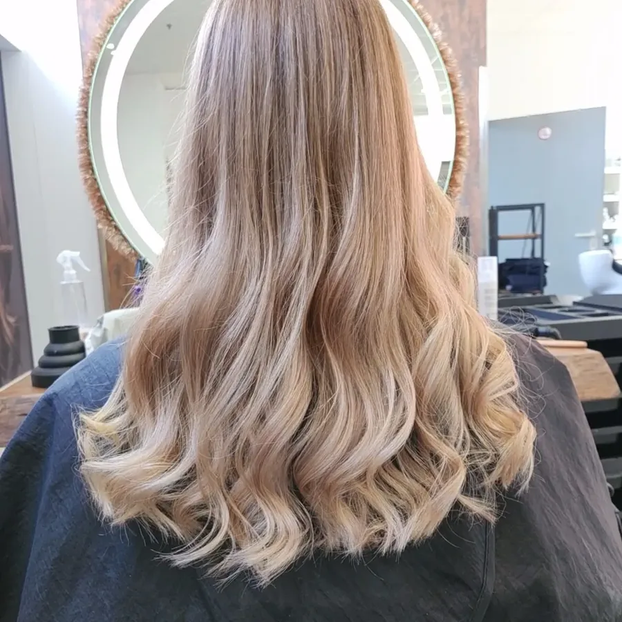 Blonde Haare mit Wellen, gestuft geschnitten.